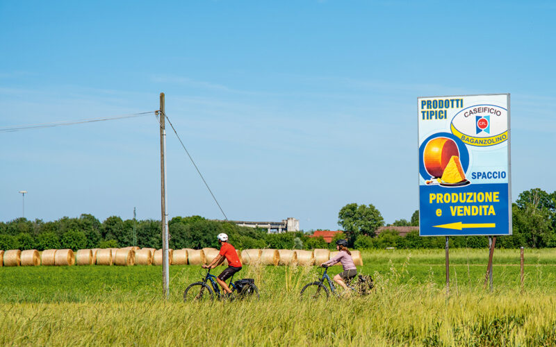 Zwei Radfahrende vor einem Werbeschild in Parma