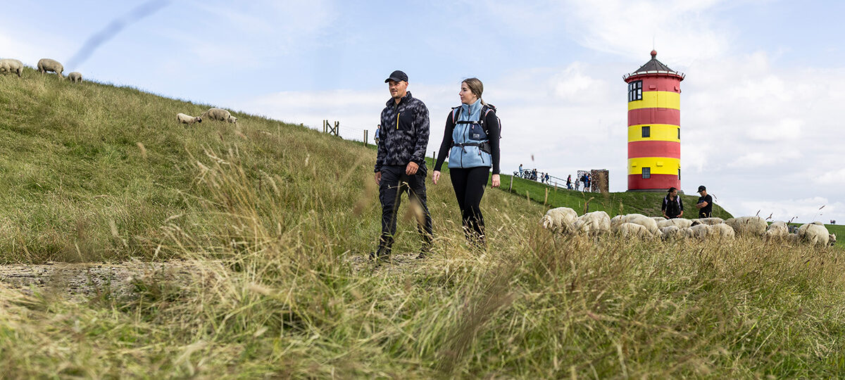 Zwei Wanderer an der Nordsee vor Leuchtturm